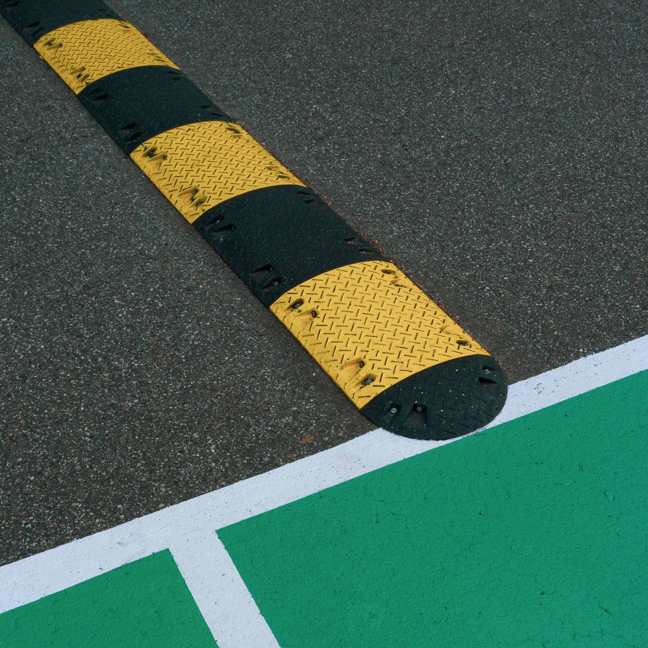 Close-up of a speed bump and colorful road markings on a pavement.