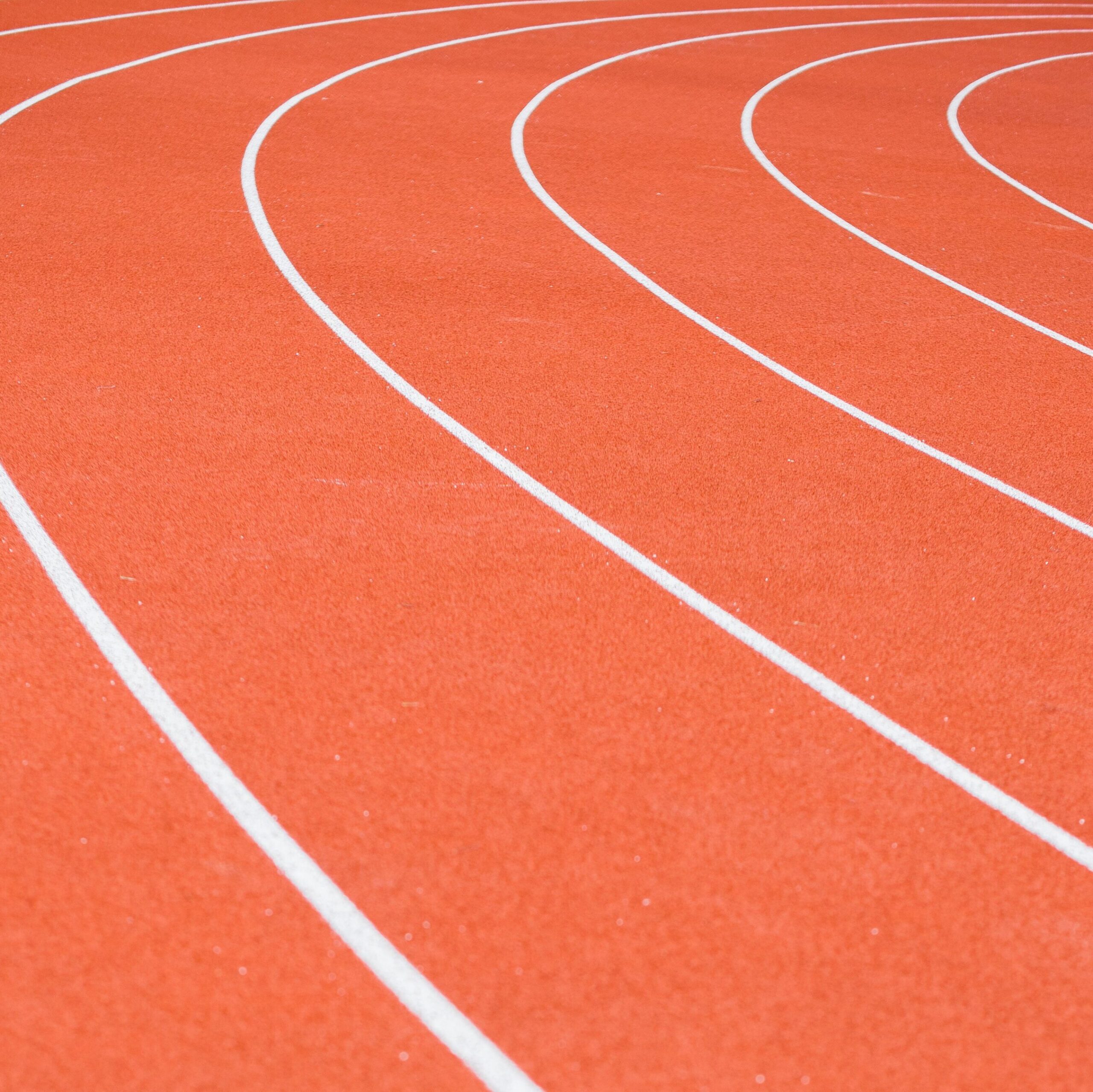 Red running track with distinct white lane markings and rubberized surface.